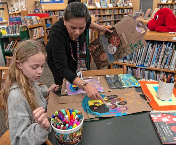 Molly Valentine, a Crocker Farm Elementary student, works with librarian and teacher Waleska Santiago-Centeno on panels for the Memory Project. For the project, students created hanging banners featuring women from picture books they have read from the library.