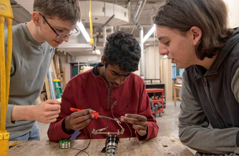 ARHS students Will Larson, left, Yatharth Rajakumar and Max Costa work on soldering a chip for the InvenTeam project garment called SARAH, Search And Rescue Assistant Hardware. The project will transmit vital signs of search and rescue personnel while they are on a mission.