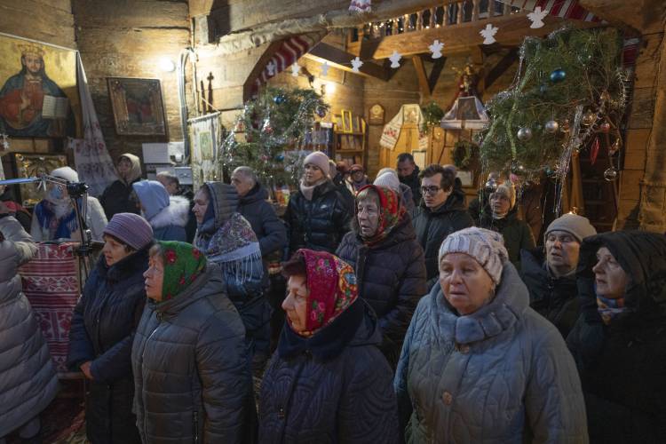 People pray as they attend Christmas service in a church in the village of Pirogovo outside capital Kyiv, Ukraine, Monday, Dec. 25, 2023.