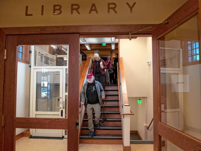 Art and Maura Keene descend the stairs to the lower-level addition, where patrons enter the building, during the reopening of the North Amherst Library on Monday.
