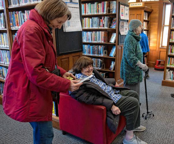 Pam Rooney looks over a DVD with Hilda Greenbaum during the reopening of the North Amherst Library on Monday. 